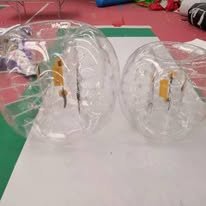 Two clear inflatable bubble balls with yellow inner straps, no people