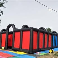 Black and red inflatable laser-tag arena with high walls on a grass field