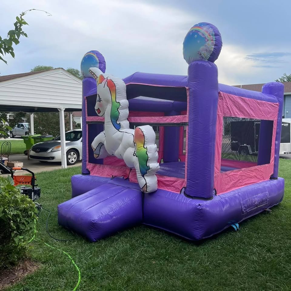 Purple and pink unicorn bounce house with a 3D white unicorn on a lawn